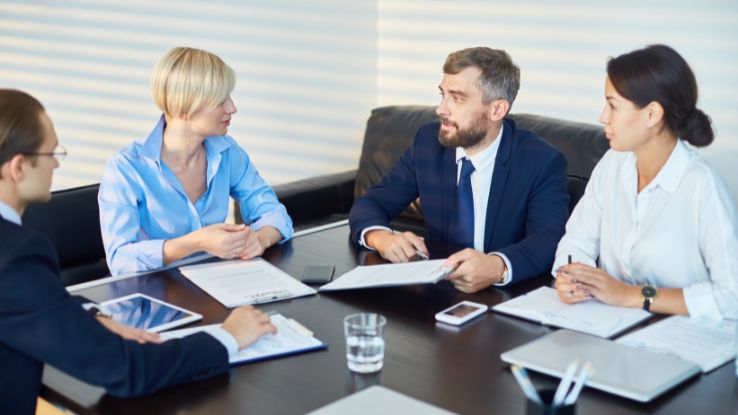 persone parlano in ufficio sedute a un tavolo