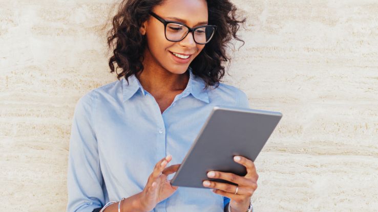 ragazza con tablet sorride perché consapevole del tempo che risparmia con l'automatizzazione delle operazioni finanziarie ripetitive