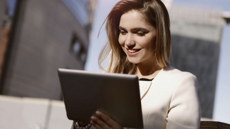 ragazza sorridente con tablet perché consapevole dei benefici della tesoreria digitalizzata